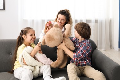 Photo of Children and their mother playing with different toys on sofa at home