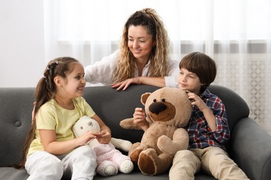 Photo of Children and their mother playing with different toys on sofa at home