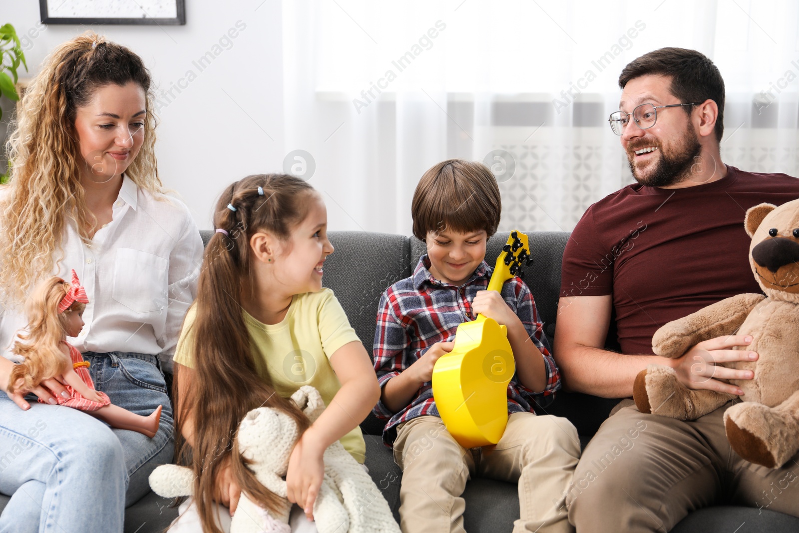 Children and their parents playing with different toys on sofa at home Photo of Children and their parents playing with different toys on sofa at home