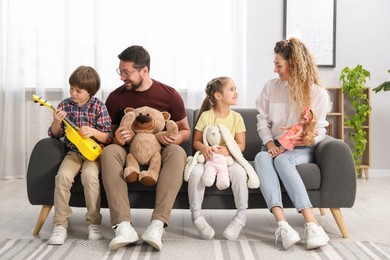 Photo of Children and their parents playing with different toys on sofa at home