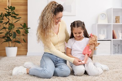 Photo of Mother and her daughter playing with doll on floor at home