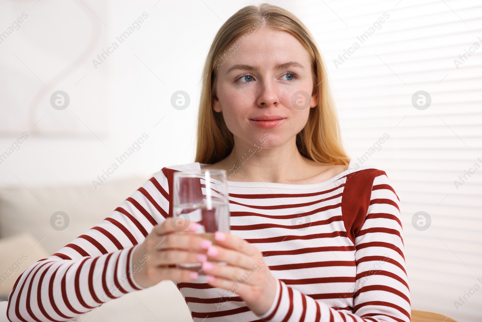 Young woman with glass of water at home Photo of Young woman with glass of water at home