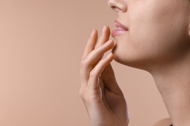 Photo of Young woman with lip balm on beige background, closeup. Space for text