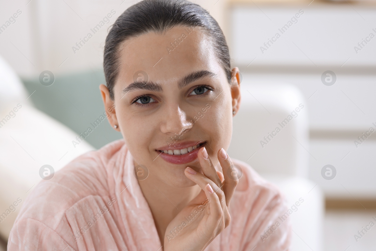 Young woman with lip balm at home Photo of Young woman with lip balm at home