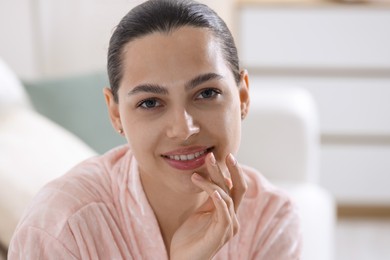 Photo of Young woman with lip balm at home
