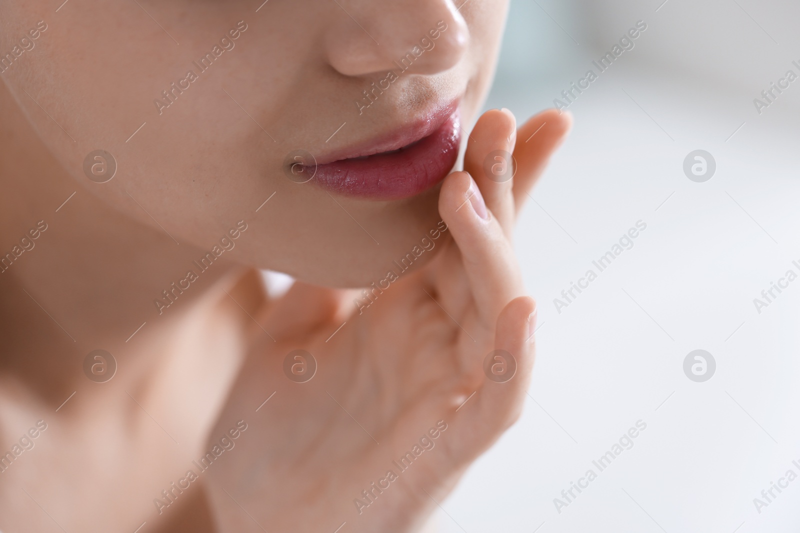 Young woman with lip balm at home, closeup. Space for text Photo of Young woman with lip balm at home, closeup. Space for text