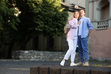 Photo of Lovely couple walking together on city street, space for text