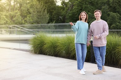Photo of Lovely couple walking together on city street, space for text