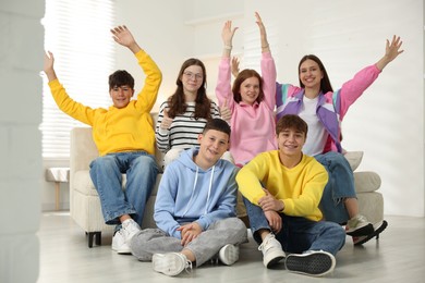 Photo of Group of excited teenagers on sofa at home