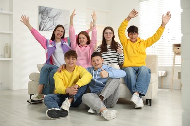 Photo of Group of excited teenagers on sofa at home