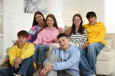 Photo of Group of happy teenagers on sofa at home