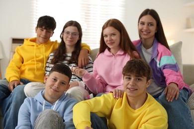 Photo of Group of happy teenagers on sofa at home