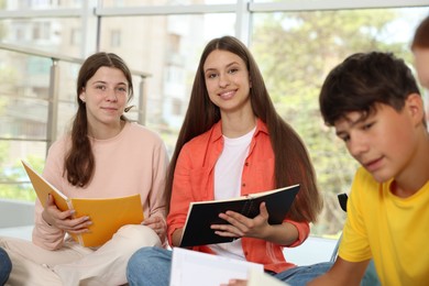 Photo of Group of teenagers with notebooks studying together indoors