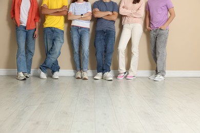Photo of Group of teenagers near beige wall indoors, closeup