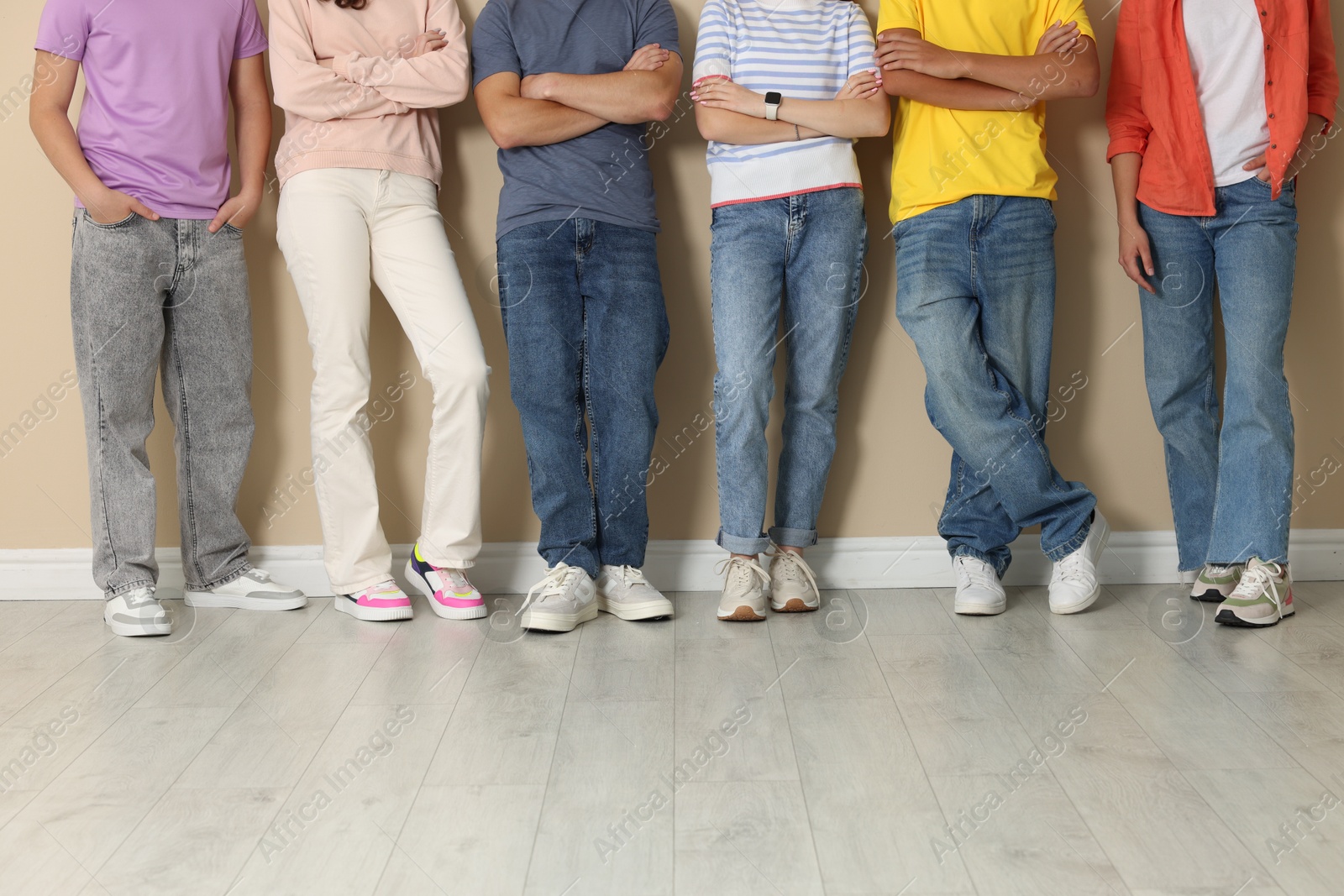 Group of teenagers near beige wall indoors, closeup Photo of Group of teenagers near beige wall indoors, closeup