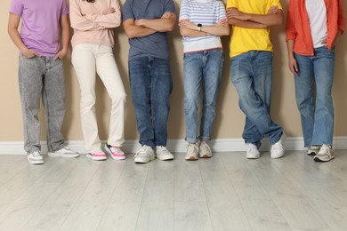 Photo of Group of teenagers near beige wall indoors, closeup
