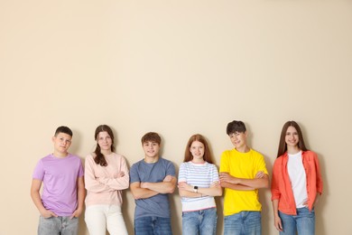 Photo of Group of teenagers near beige wall indoors. Space for text