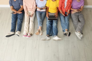 Photo of Group of teenagers with laptop and smartphones indoors, above view