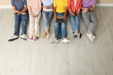 Photo of Group of teenagers with laptop and smartphones indoors, above view