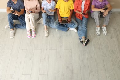 Photo of Group of teenagers with laptop and smartphones indoors, above view