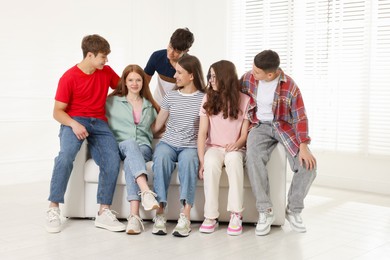 Photo of Group of happy teenagers on sofa indoors