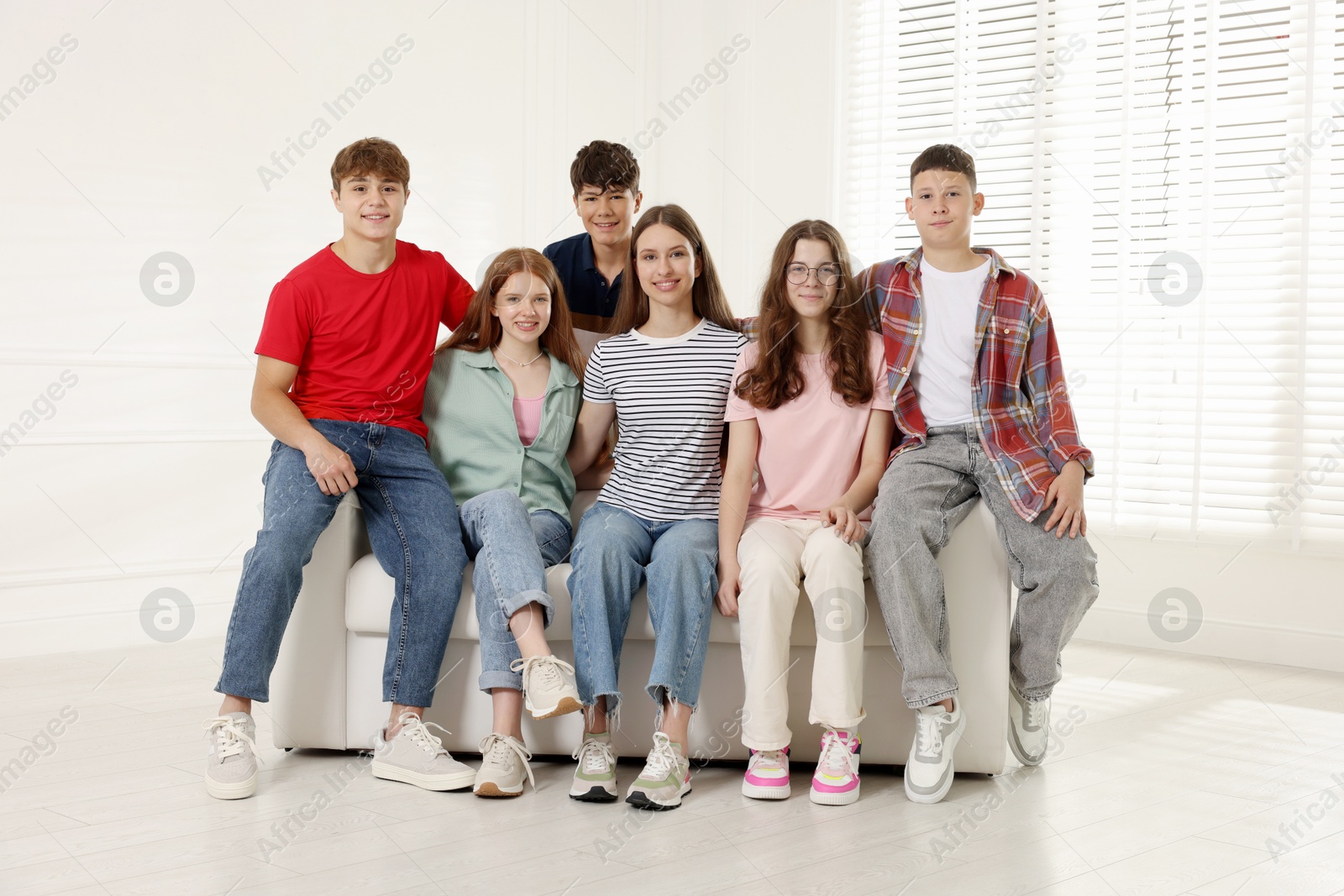 Group of happy teenagers on sofa indoors Photo of Group of happy teenagers on sofa indoors