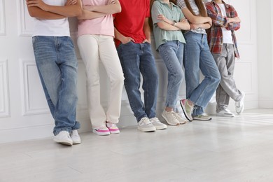 Photo of Group of teenagers near white wall indoors, closeup