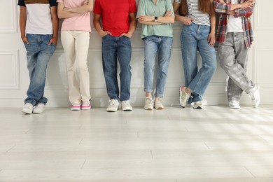 Photo of Group of teenagers near white wall indoors, closeup