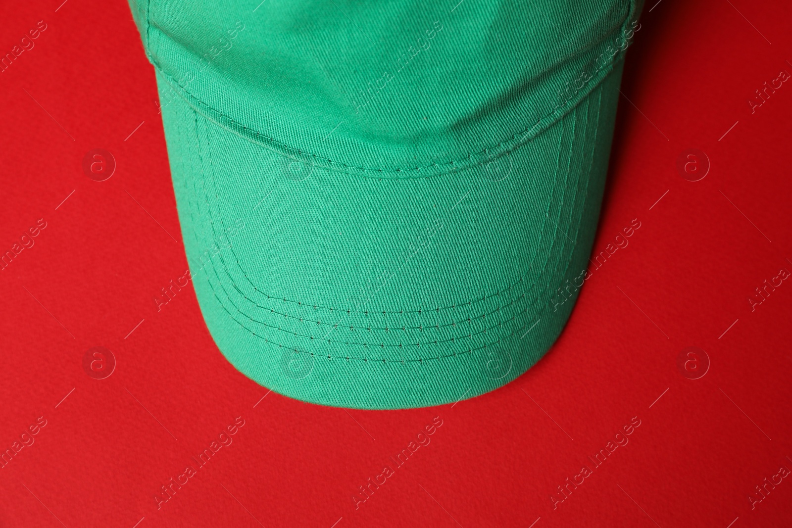 Green baseball hat on red background, top view. Mockup for design Photo of Green baseball hat on red background, top view. Mockup for design