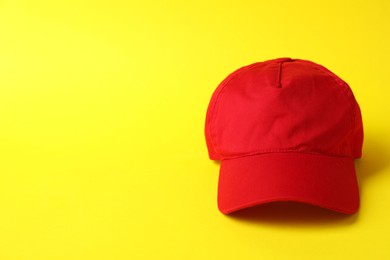 Photo of Red baseball hat on yellow background, space for text