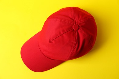 Photo of Red baseball hat on yellow background, top view. Mockup for design