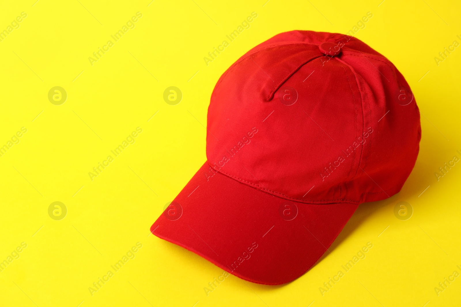Red baseball hat on yellow background, closeup. Space for text Photo of Red baseball hat on yellow background, closeup. Space for text