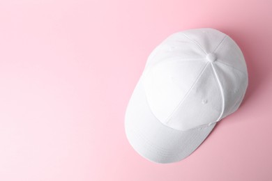 Photo of White baseball hat on pink background, top view. Space for text