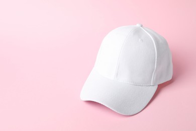 Photo of White baseball hat on pink background, space for text