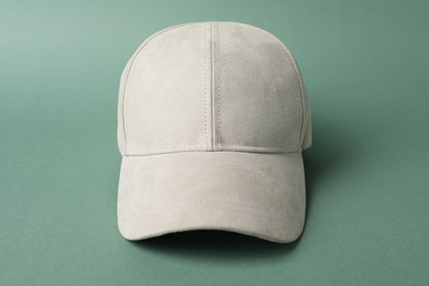Photo of Beige baseball hat on green background, closeup. Mockup for design