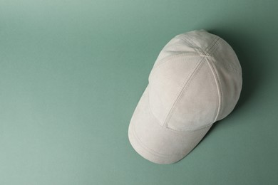 Photo of Beige baseball hat on green background, top view. Space for text