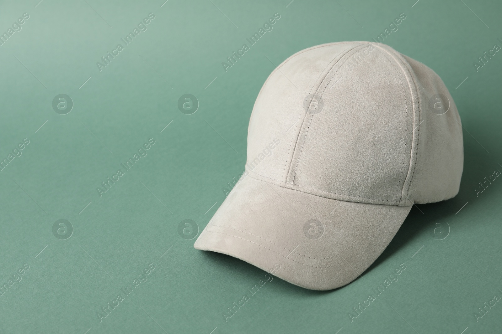 Photo of Beige baseball hat on green background, space for text