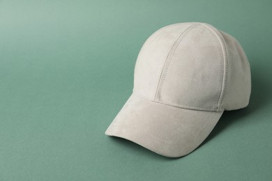 Photo of Beige baseball hat on green background, space for text