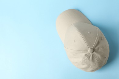 Photo of Beige baseball hat on light blue background, top view. Space for text