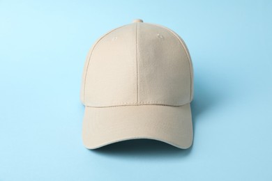 Photo of Beige baseball hat on light blue background, closeup. Mockup for design
