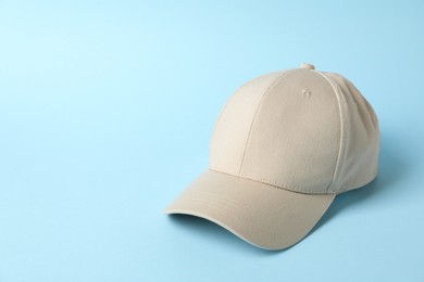 Photo of Beige baseball hat on light blue background, space for text