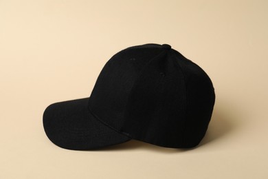 Photo of One black baseball hat on beige background