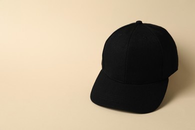 Photo of Black baseball hat on beige background, space for text