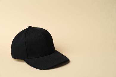 Photo of Black baseball hat on beige background, space for text