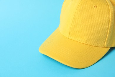 Photo of Yellow baseball hat on light blue background, closeup. Space for text