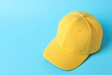 Photo of Yellow baseball hat on light blue background, above view. Space for text