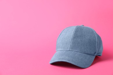 Photo of Denim baseball hat on pink background, closeup. Space for text