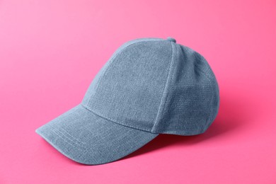 Photo of Denim baseball hat on pink background, closeup