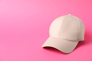 Photo of Beige baseball hat on pink background, space for text