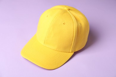 Photo of Yellow baseball hat on violet background, closeup. Mockup for design